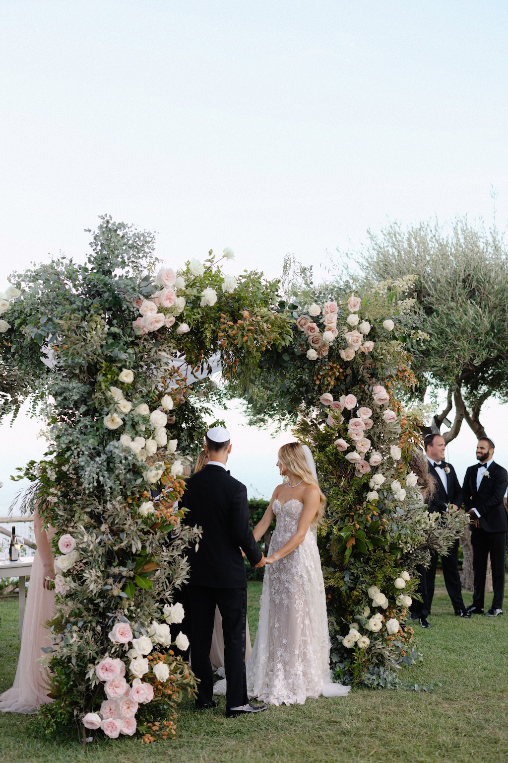 chuppah with spontaneous greenery and roses in light palette color
