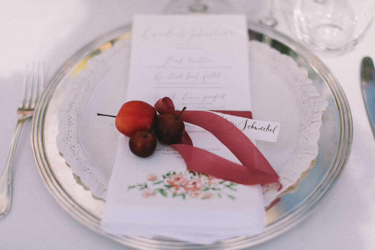idea segnaposto con nastro di seta legatovagliolo, menu scritto a mano e piccoli frutti rossi