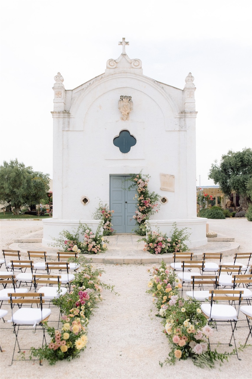 corsia di fiori con crescite spontanee con fiori colorati e arco scomposto per matrimonio nella chiesetta in masseria San Giovanni in Puglia