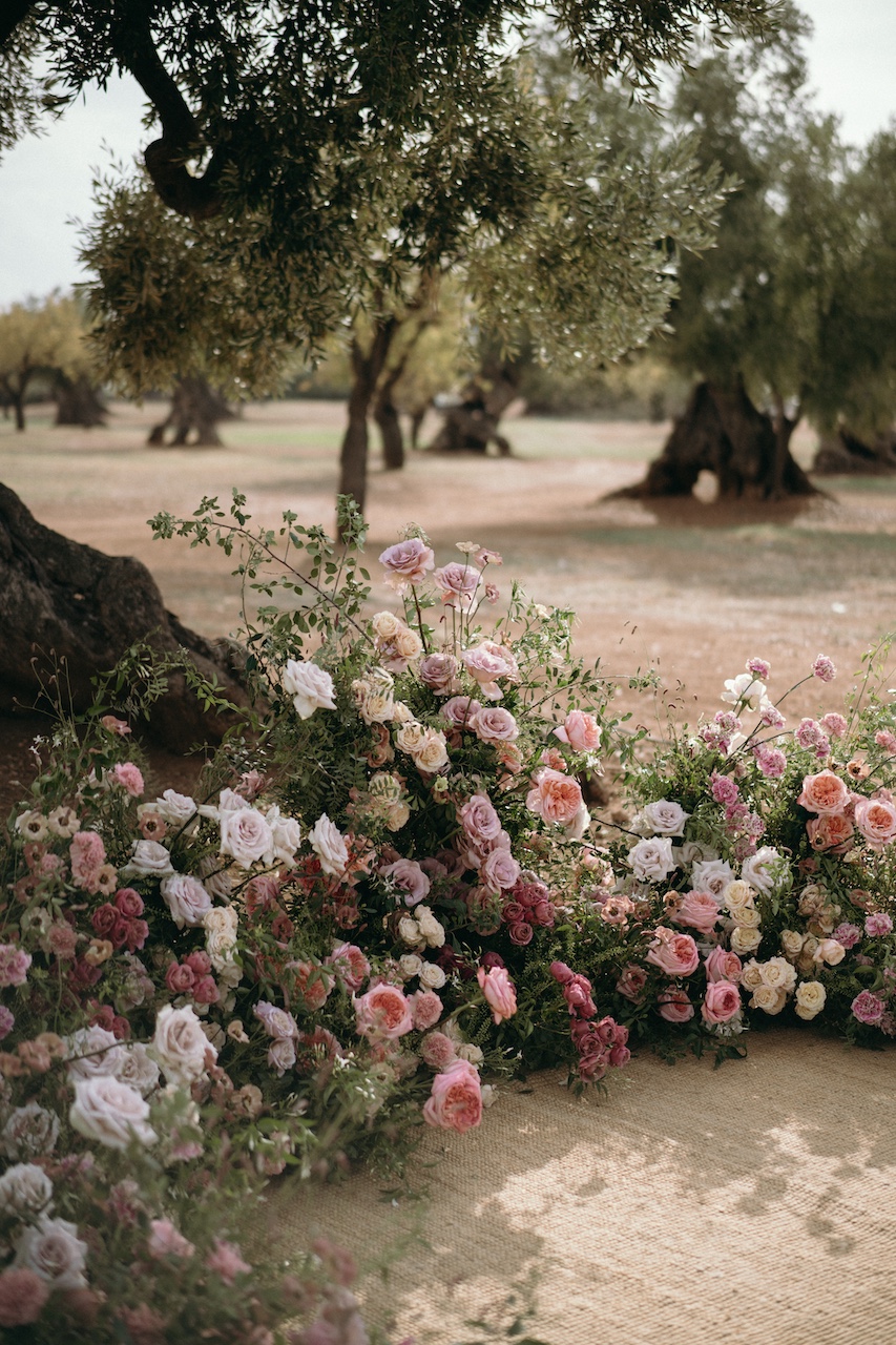 dettaglio semicerchio floreale con rose e verde per matrimonio all'aperto sotto gli ulivi di Masseria Pettolecchia