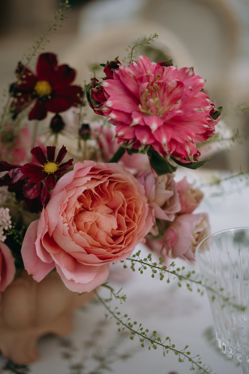 dettaglio centrotavola floreale con diverse texture di fiori con rose, cosmos e dalie per cena di matrimonio all'aperto