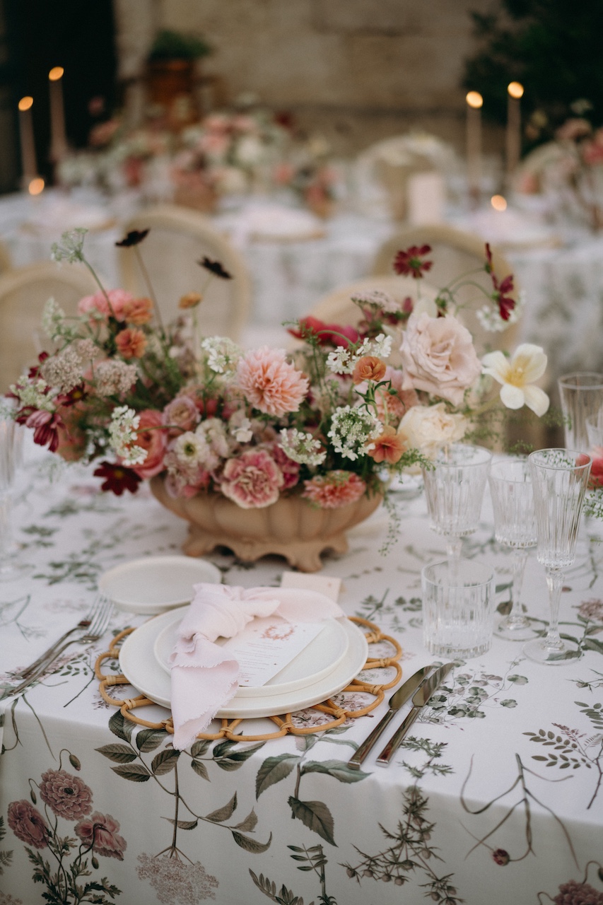 mise en place floreale per cena di matrimonio all'aperto dai colori desaturati con sottopiatto in bambù