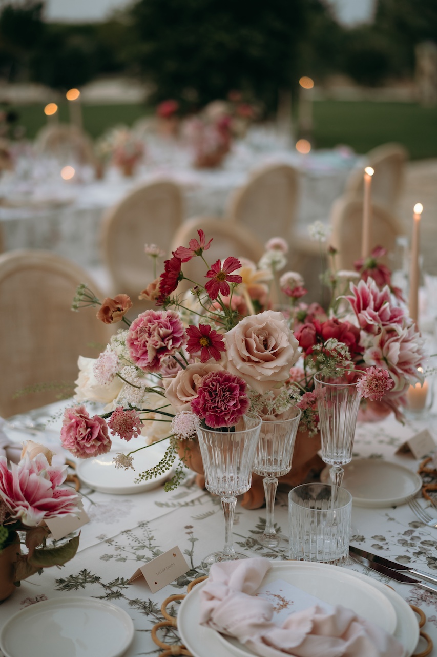 dettaglio centrotavola floreale per cena di matrimonio dai colori detasurati su tovaglia con stampa botanica